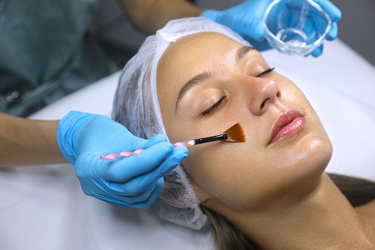 Cosmetologist applying chemical peel product on client's face